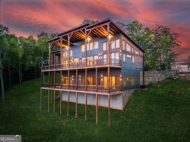 885 Tower Rd, Mineral Bluff, GA 30559 - back of house at dusk with board and batten siding, a lawn, and a balcony