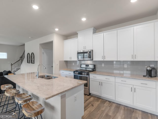 kitchen with stainless steel appliances, a sink, decorative backsplash, white cabinetry, and recessed lighting