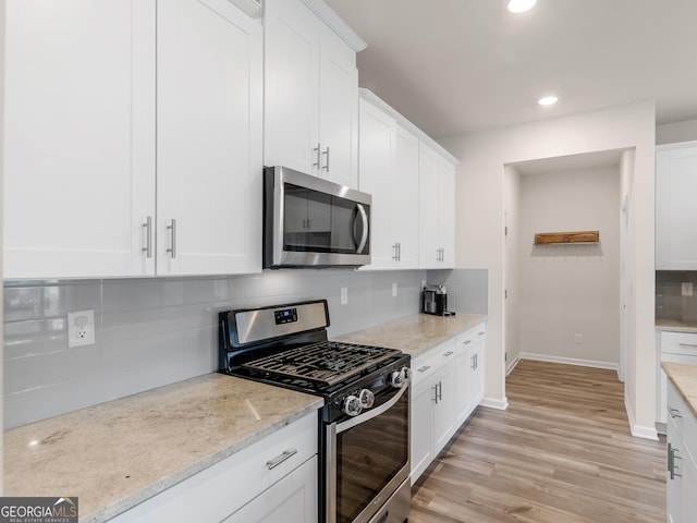 kitchen featuring stainless steel appliances, tasteful backsplash, recessed lighting, light wood-style floors, and white cabinetry