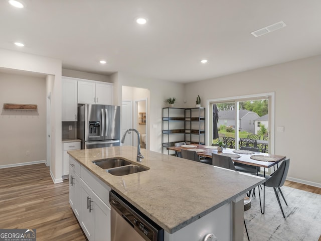 kitchen with stainless steel appliances, a sink, light wood-style floors, baseboards, and recessed lighting