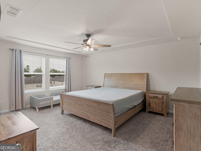 carpeted bedroom with a tray ceiling, baseboards, and ceiling fan