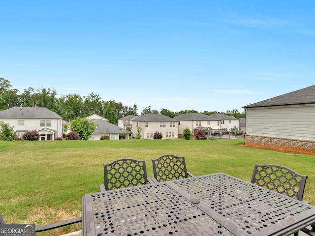view of grassy yard with outdoor dining area and a residential view