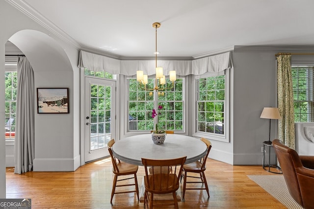 2332 Autumn Maple Dr, Braselton, GA 30517 - dining space featuring a chandelier, ornamental molding, baseboards, arched walkways, and light wood-style floors