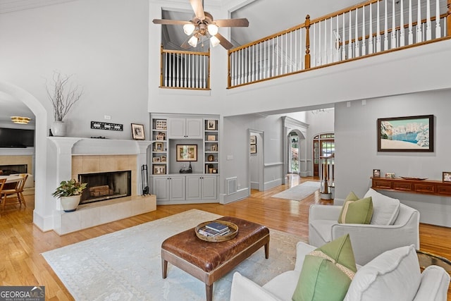 2332 Autumn Maple Dr, Braselton, GA 30517 - living area with arched walkways, a tile fireplace, ceiling fan, light wood-type flooring, and a towering ceiling