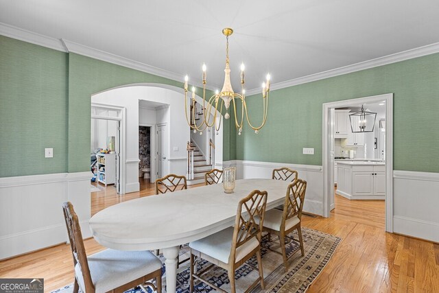 2332 Autumn Maple Dr, Braselton, GA 30517 - dining area with arched walkways, crown molding, a wainscoted wall, stairs, and a chandelier