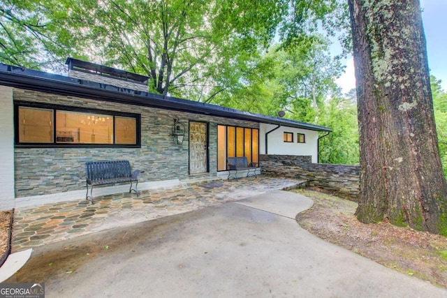 view of front of house with stone siding and a patio