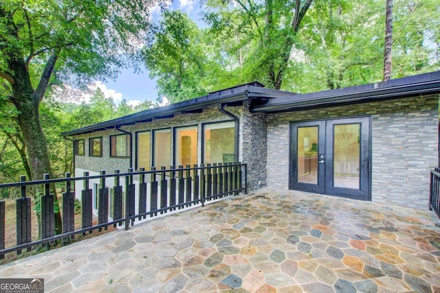 rear view of property featuring french doors, stone siding, and a patio area