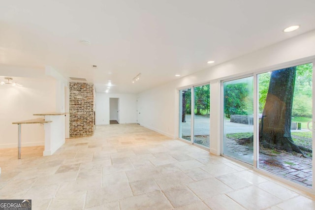 unfurnished living room featuring stone tile floors, baseboards, and recessed lighting