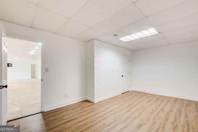 unfurnished room featuring a paneled ceiling, wood finished floors, and baseboards