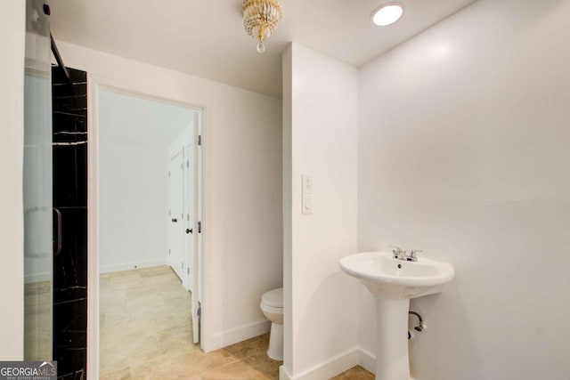 bathroom featuring toilet, a sink, and baseboards