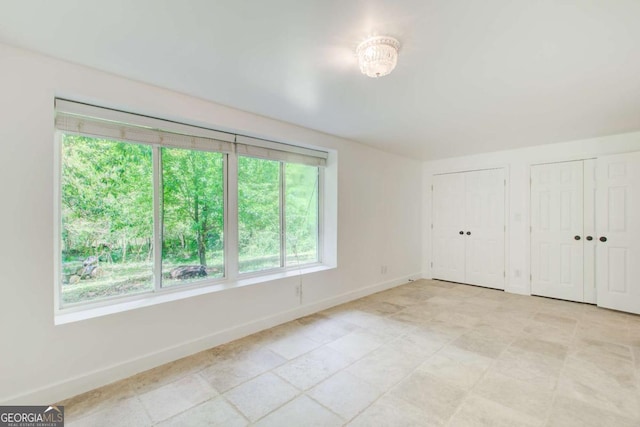 unfurnished bedroom with baseboards and multiple closets