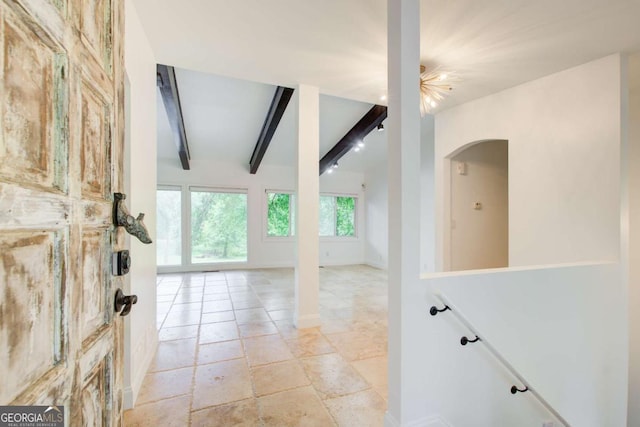 entrance foyer with arched walkways, baseboards, and light stone finish flooring