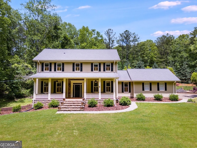 colonial inspired home with a porch, a front yard, and view of scattered trees