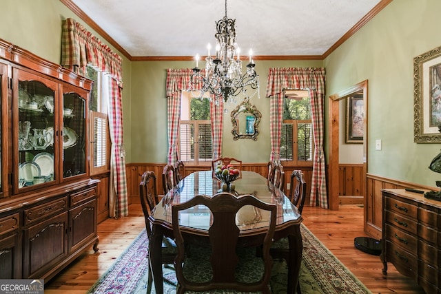dining space featuring a wainscoted wall, a chandelier, light wood-style floors, crown molding, and wood walls
