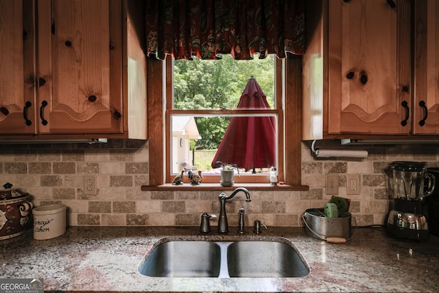 kitchen with a sink, backsplash, and stone countertops