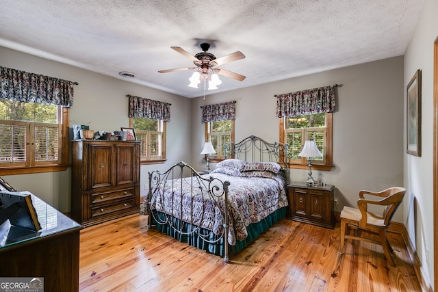 bedroom with light wood-style flooring, a textured ceiling, and ceiling fan
