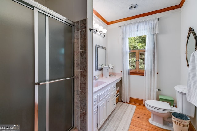 bathroom featuring crown molding, wood finished floors, a shower stall, toilet, and vanity