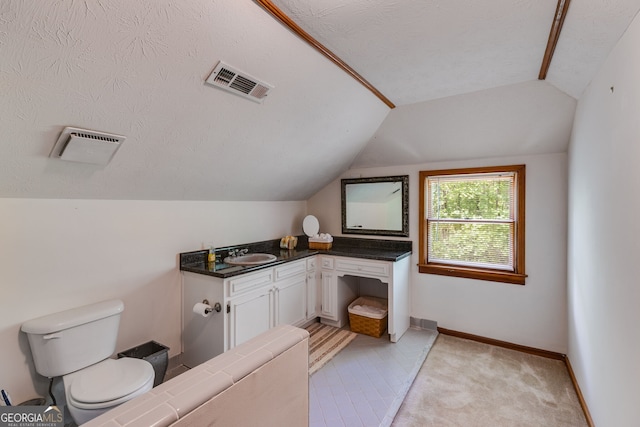 bathroom with vaulted ceiling, toilet, vanity, and baseboards