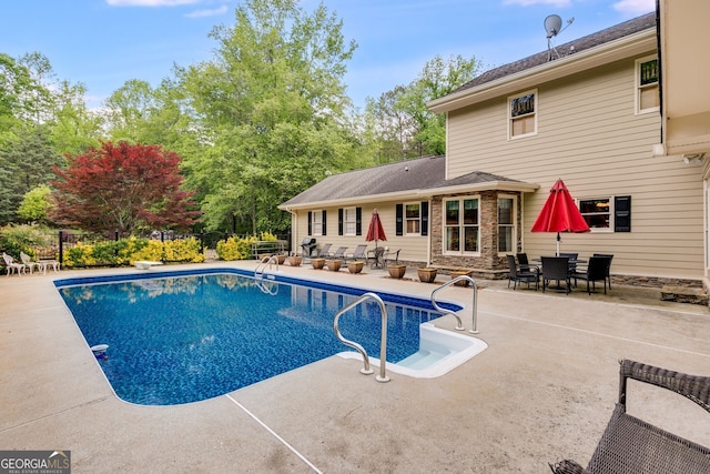 view of pool with a patio area, fence, and a diving board