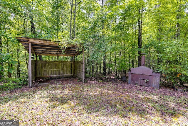 view of yard with a detached carport and a view of trees