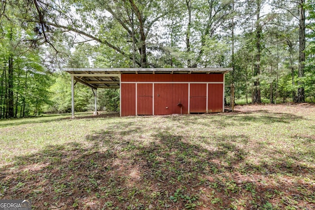 view of pole building with a carport, a forest view, and a lawn