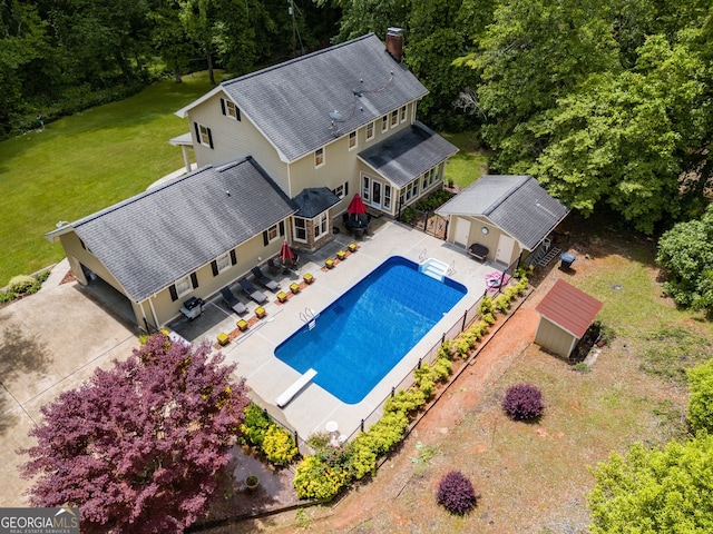 swimming pool featuring an outbuilding, a diving board, and a patio area