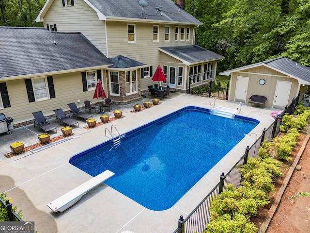 view of swimming pool with a patio, a diving board, an outbuilding, fence, and outdoor dining area