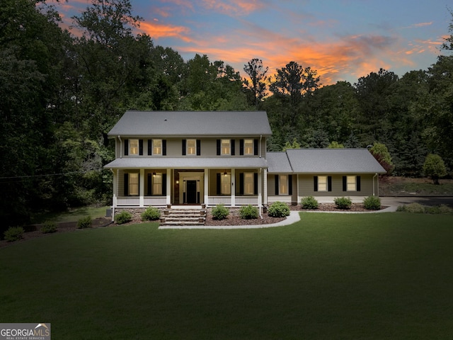 colonial home featuring a porch and a lawn