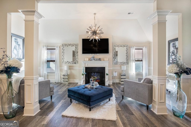 living area with ornate columns, dark wood finished floors, a glass covered fireplace, and lofted ceiling