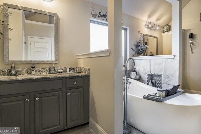 bathroom with a soaking tub, vanity, and baseboards