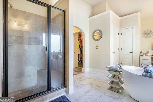 bathroom featuring marble finish floors, a shower stall, a freestanding tub, baseboards, and a walk in closet