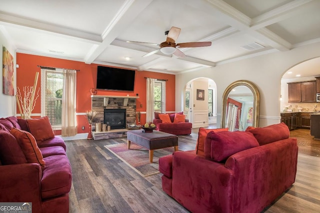 living room featuring arched walkways, coffered ceiling, beam ceiling, healthy amount of natural light, and wood finished floors