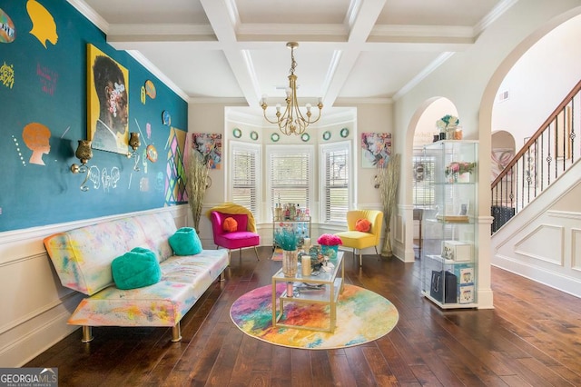 living area featuring a chandelier, coffered ceiling, beamed ceiling, hardwood / wood-style floors, and a wainscoted wall