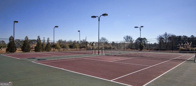 view of tennis court featuring community basketball court and fence
