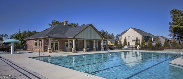 community pool with a patio area and fence