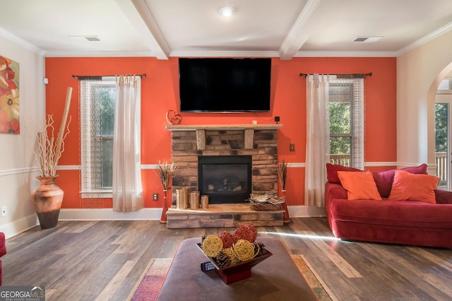 living area featuring crown molding, wood finished floors, beamed ceiling, arched walkways, and a stone fireplace