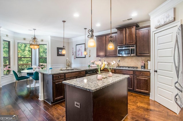 kitchen with appliances with stainless steel finishes, a sink, a peninsula, a center island, and light stone counters