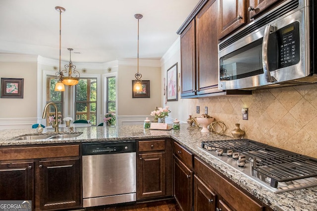 kitchen with stainless steel appliances, a sink, light stone counters, tasteful backsplash, and hanging light fixtures