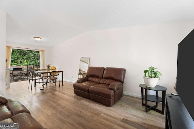 living area featuring wood finished floors, lofted ceiling, and baseboards
