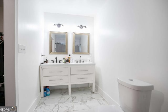 bathroom featuring marble look tiles, baseboards, toilet, and double vanity