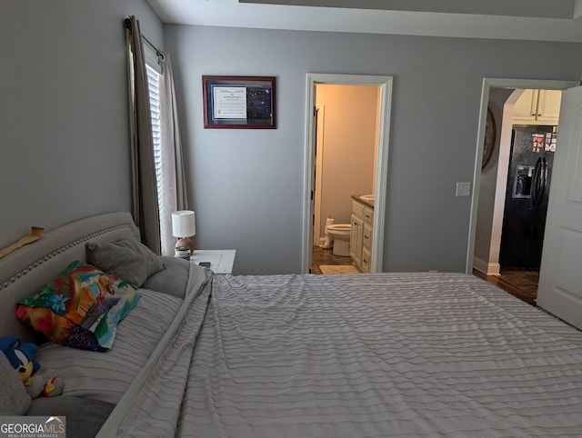 bedroom featuring black fridge with ice dispenser and ensuite bathroom