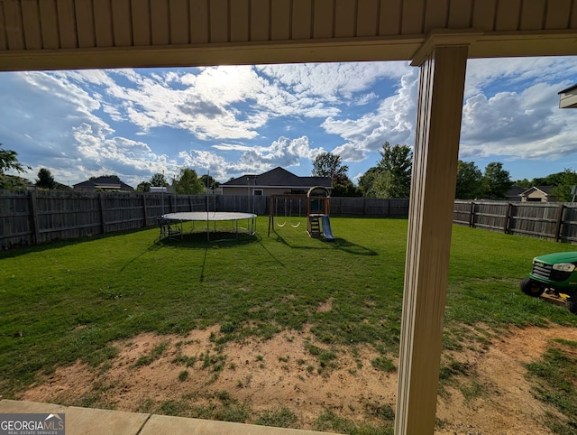 view of yard with a trampoline and a playground