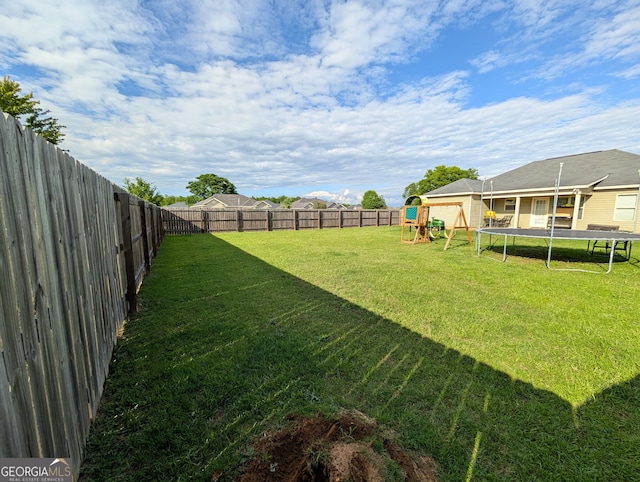 view of yard with a trampoline and a playground