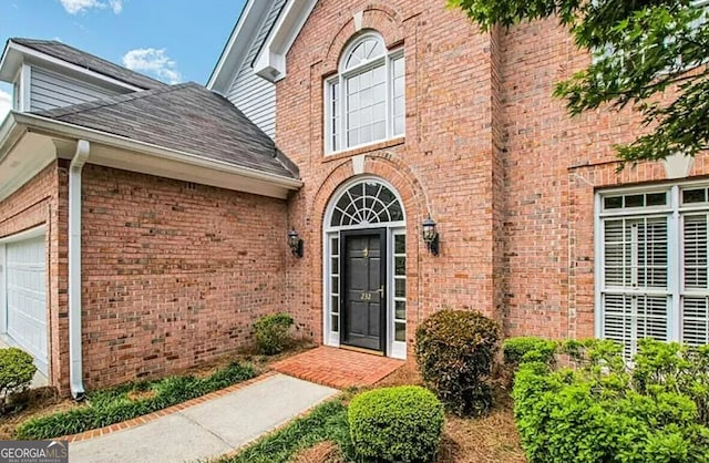 232 Spalding Gates Dr, Atlanta, GA 30328 - view of exterior entry with brick siding, an attached garage, and a shingled roof