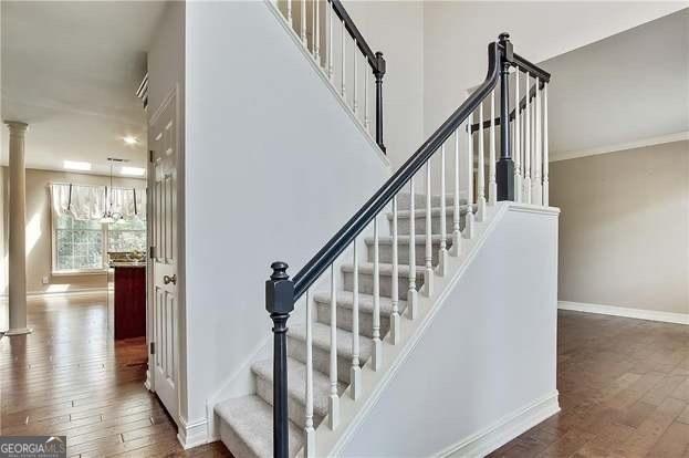 232 Spalding Gates Dr, Atlanta, GA 30328 - staircase featuring hardwood / wood-style flooring, baseboards, decorative columns, and a chandelier