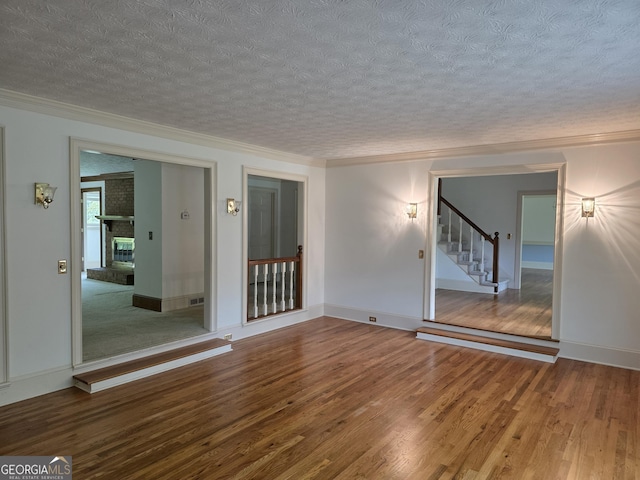2451 Old Salem Cir SE, Conyers, GA 30013 - unfurnished room featuring a textured ceiling, wood finished floors, stairway, crown molding, and a fireplace