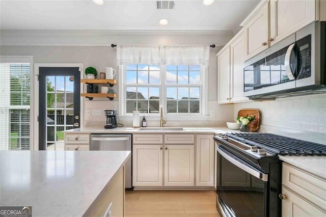 kitchen featuring stainless steel appliances, a sink, crown molding, tasteful backsplash, and recessed lighting
