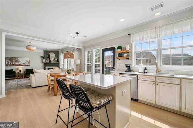 kitchen with dishwasher, a sink, light countertops, a kitchen island, and a breakfast bar area