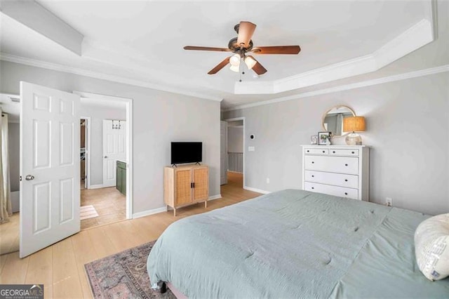 bedroom featuring a raised ceiling, light wood-style flooring, ornamental molding, and a ceiling fan