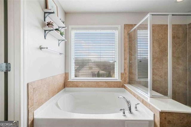 bathroom featuring plenty of natural light, a bath, and a tile shower